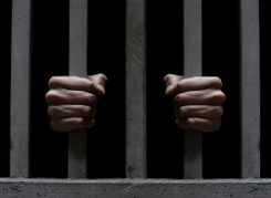 Hands holding jail bars