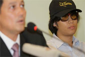 Wearing a baseball cap and sunglasses, Aekawit Thongdeeworakul appeared at a press conference in Bangkok