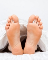 Bare feet in bed. Image from Shutterstock